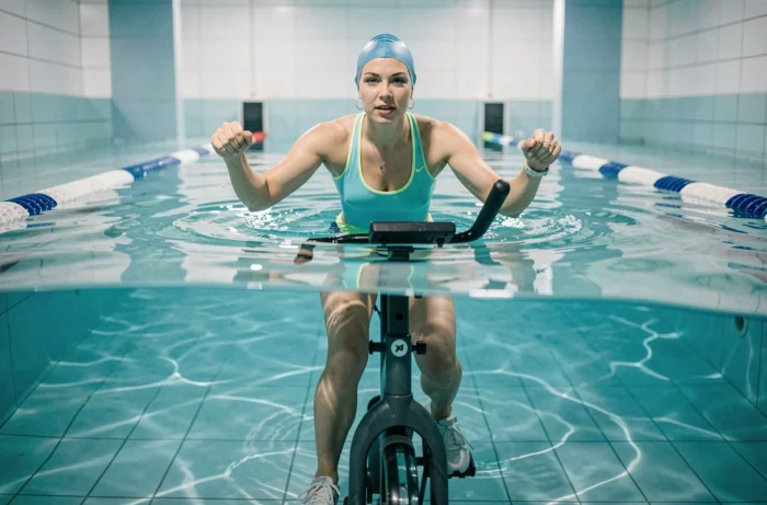 Femme pratiquant l'aquabike dans une piscine intérieure moderne à Orléans, vue à hauteur d'eau