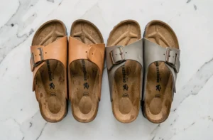 Comparaison côte à côte d'une vraie Birkenstock Arizona et d'une contrefaçon sur marbre blanc, montrant les différences de qualité de fabrication